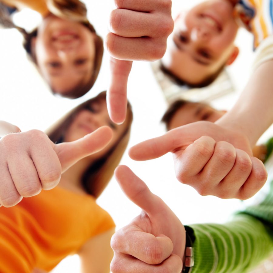 Below angle of happy teens showing thumbs up